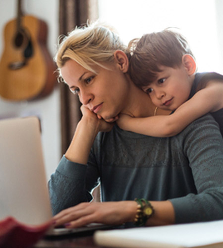 Woman reviewing budget with son hugging her from behind