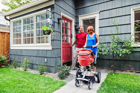Couple pushing stroller in front of house for sale