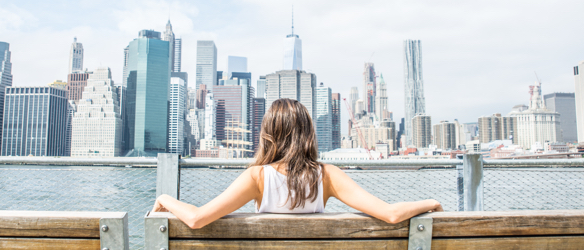 Woman sitting on bench looking at city skyline